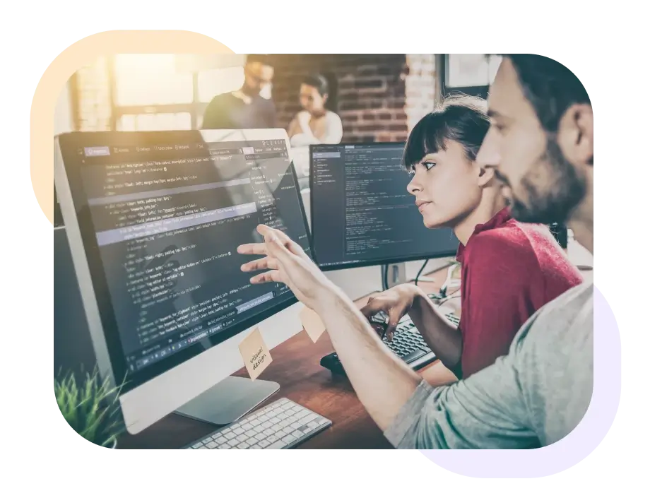 Zwei Personen sitzen vor einem Bildschirm mit Codezeilen.