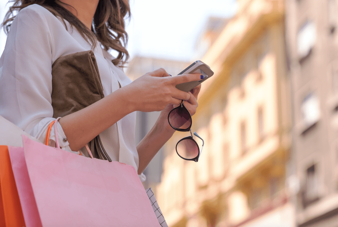 Frau beim Einkaufen mit Smartphone in der Hand