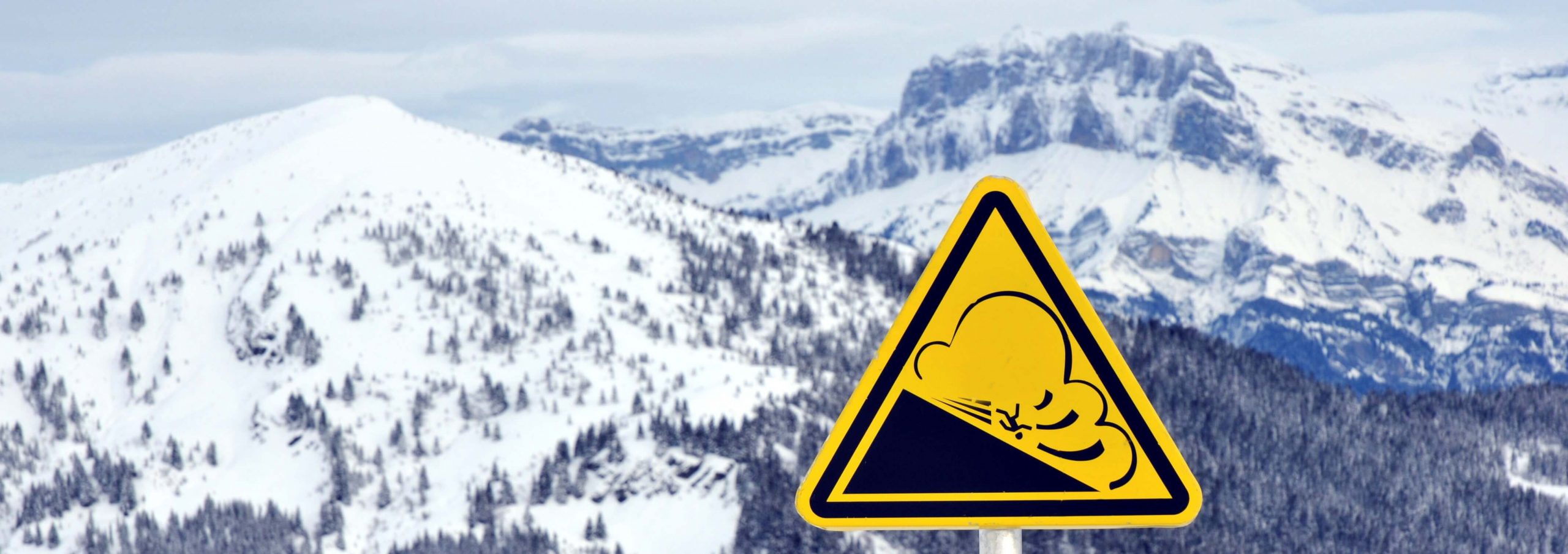Lawinene-Warnschild mit Bergen im Hintergrund